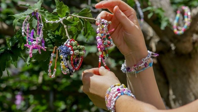 Swifties fix bracelets on a tree in the city centre in Vienna on Thursday, Aug.8, 2024. Organizers of three Taylor Swift concerts in the stadium in Vienna this week called them off on Wednesday after officials announced arrests over an apparent plot to launch an attack on an event in the Vienna area such as the concerts. (AP Photo/Heinz-Peter Bader)