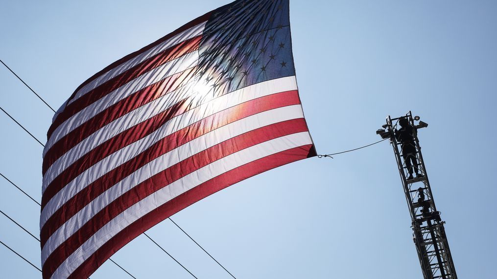 ORANGE, CALIFORNIA - SEPTEMBER 22: A firefighter helps take down a U.S. flag which had been hoisted between two ladder trucks on September 22, 2020 in Orange, California. (Photo by Mario Tama/Getty Images)