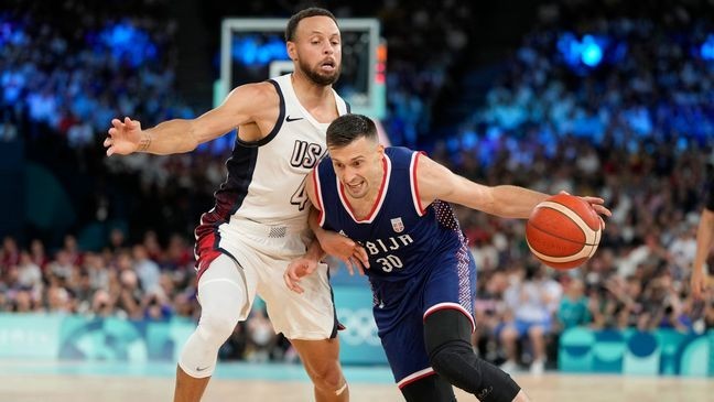 Aleksa Avramovic (30), of Serbia drives past United States' Stephen Curry (4) during a men's semifinals basketball game at Bercy Arena at the 2024 Summer Olympics, Thursday, Aug. 8, 2024, in Paris, France. (AP Photo/Michael Conroy)