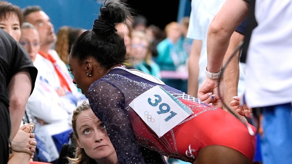 Simone Biles (391), of the United States, speaks to coaches after bobbling while warming up before her routine in the women's artistic gymnastics individual floor finals at Bercy Arena at the 2024 Summer Olympics, Monday, Aug. 5, 2024, in Paris, France. (AP Photo/Abbie Parr)